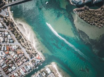 Aerial view of seascape by city during sunny day