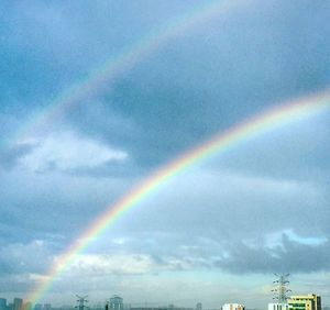 Rainbow over town against cloudy sky