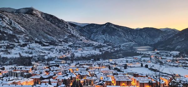 Town by mountains against sky during winter