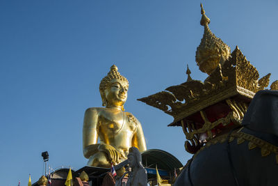 Low angle view of statue against temple against clear sky