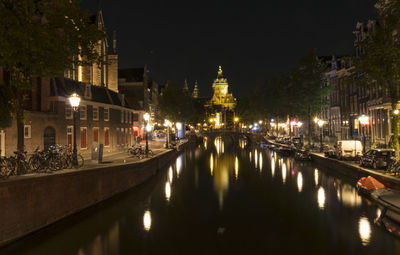 Illuminated canal amidst buildings in city at night