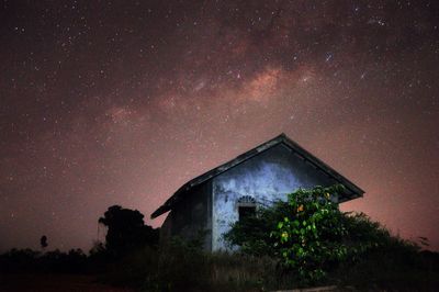 House on field against starry sky at night