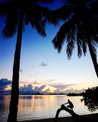 Silhouette palm tree on beach against sky during sunset