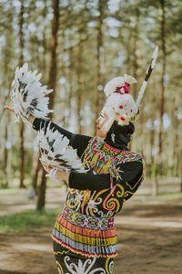 Portrait of woman with arms outstretched standing outdoors