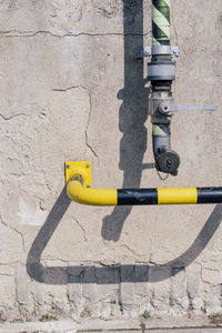 Pipe of a pumping station and safety bar in yellow black on a concrete wall.