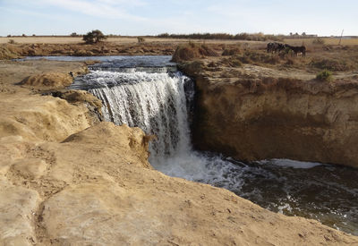 Scenic view of waterfall against sky