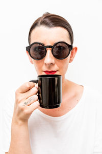 Close-up portrait of young woman holding camera over white background