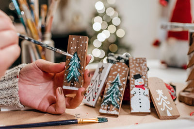 Selective focus, close-up of hand holding paintbrush, crafting christmas ornaments.