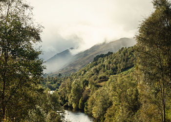 Scenic view of river amidst mountains against sky