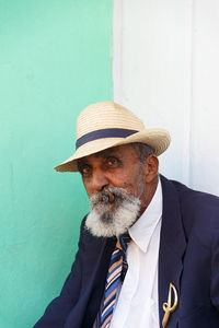 Portrait of man smoking cigar while sitting against wall