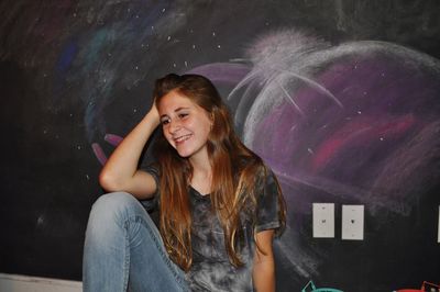 Rear view of woman standing against chalk drawing on blackboard