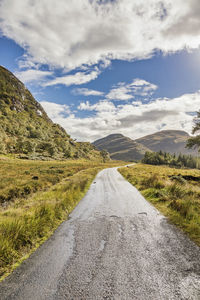 Road amidst green landscape against sky