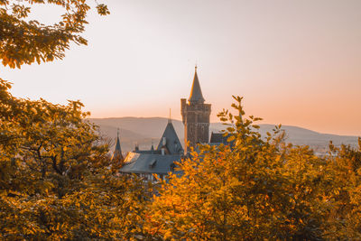 Trees and buildings against sky during autumn