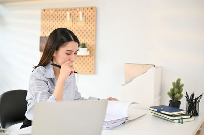 Young woman using laptop while sitting at office