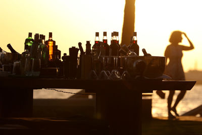 Silhouette drinks on table against clear sky during sunset