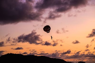 Low angle view of silhouette person parasailing against sky during sunset
