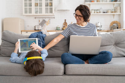 Young woman using phone while sitting on sofa