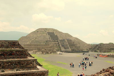 People by historic pyramid against sky