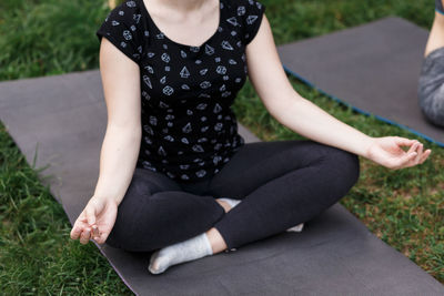 The relaxed girl is doing yoga in the park on carpet