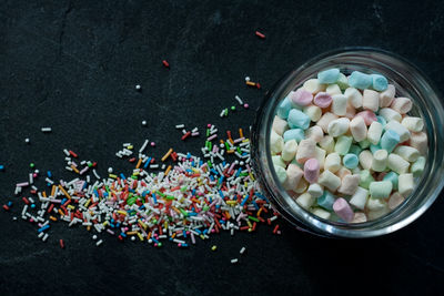 Sprinkles and a glass full of marshmallows on slate 