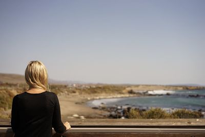 Rear view of woman looking at sea against clear sky