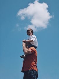 Low angle view of father carrying son on shoulders