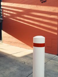 Bollard on sidewalk against wall