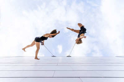 Female dancers dancing against sky