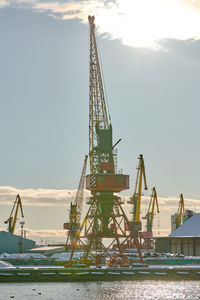 Cranes at pier against sky