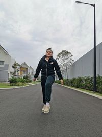 Full length portrait of young man on road against sky