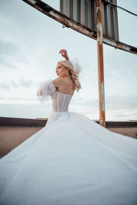 Full length of woman with arms raised against sky