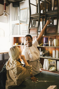 Female entrepreneur showing chairs to customer at upcycling store