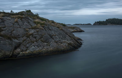 Rock formation in sea against sky