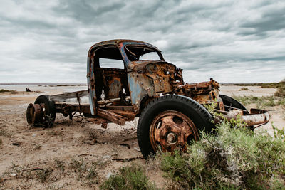Old abandoned truck on field against sky