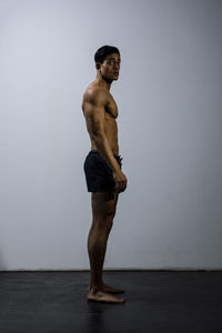 Portrait of shirtless muscular man exercising against wall