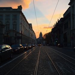 Railroad tracks in city against sky during sunset