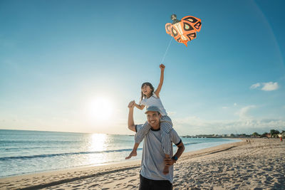 Father carrying daughter on shoulder at beach