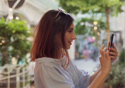 Young woman using phone while standing at city