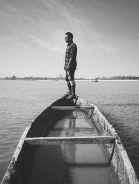 Man standing on pier over lake against sky