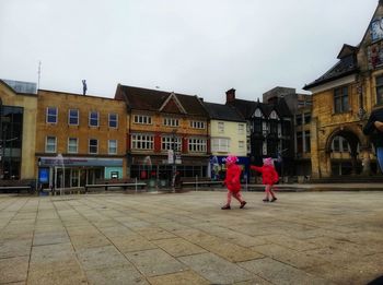 People walking on street against buildings in city