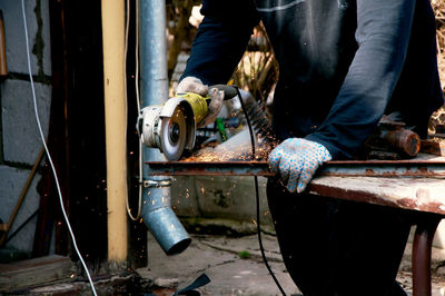 Low section of man working on metal