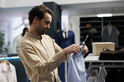 Side view of man using mobile phone while standing at home