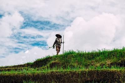 Woman standing and working on rice field against sky
