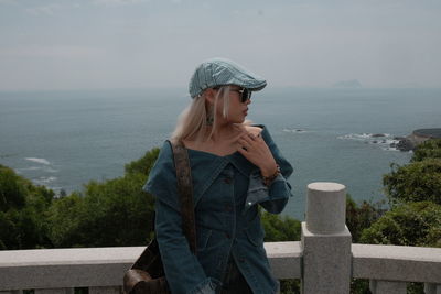 Portrait of young woman standing against sea