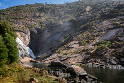 Ezaro waterfall water crashing on lake between rocks in spain