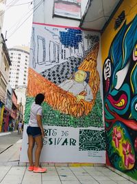 Full length rear view of woman in graffiti on building