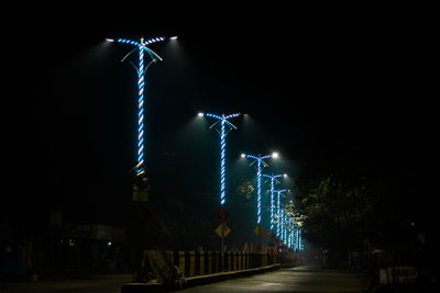 Low angle view of illuminated street against sky at night