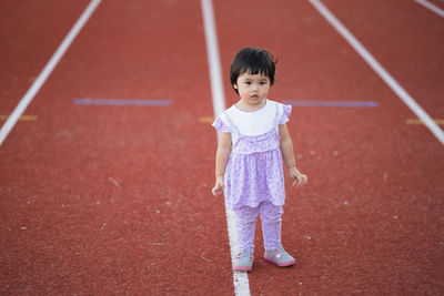 Full length portrait of cute girl standing on running track