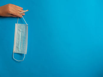 Close-up of hand holding blue against white background