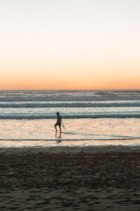 Silhouette man on beach against sky during sunset